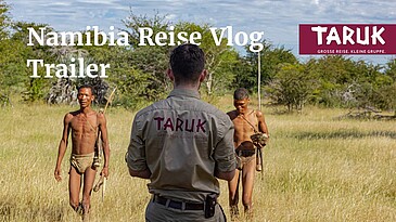 Mann filmt zwei San Buschmänner in der Steppe Afrikas