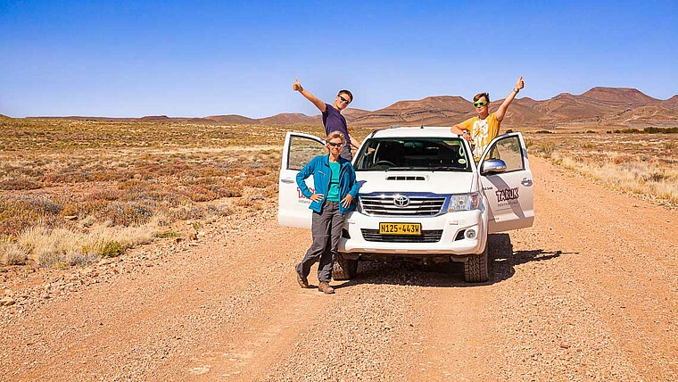 Familie mit Geländewagen auf Sandstraße in Namibia