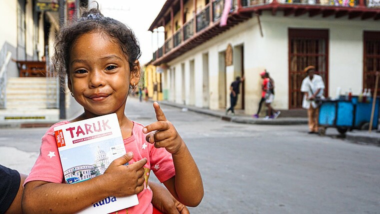 Kind mit Reiseführer lächelt in die Kamera in Santiago de Cuba