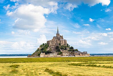 Mont Saint Michel vor grüner Wiese und blauem Himmel in Frankreich