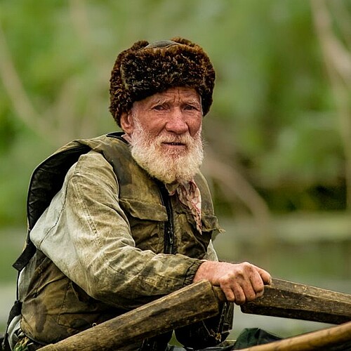 Alter Mann im Boot mit grünem Hintergrund in Rumänien.