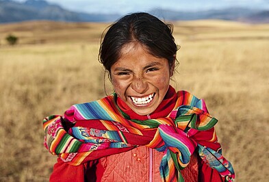 Lachendes Mädchen mit traditionellem Tuch in Peru in Südamerika