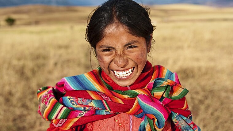Lachendes Mädchen mit traditionellem Tuch in Peru in Südamerika