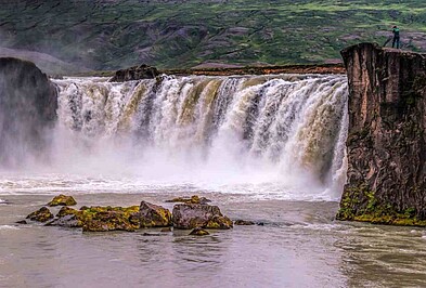 Tourist blick von einer kleinen Klippe auf die Godafoss Wasserfälle in Island