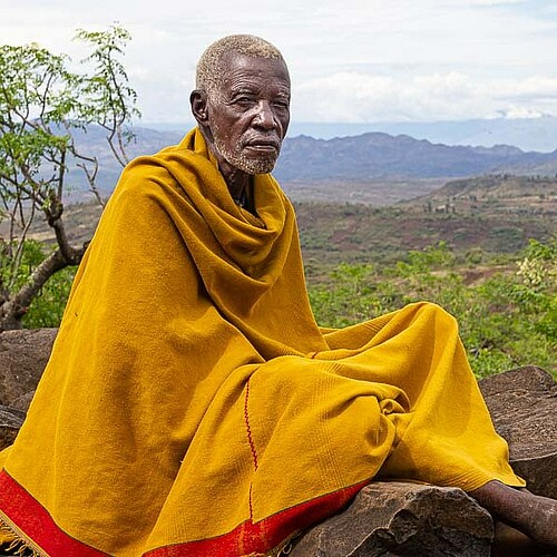Einheimischer Äthiopier-mit gelber Decke auf Felsen in Aethiopien