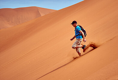 Mann läuft Düne herunter in Sossusvlei Namibia