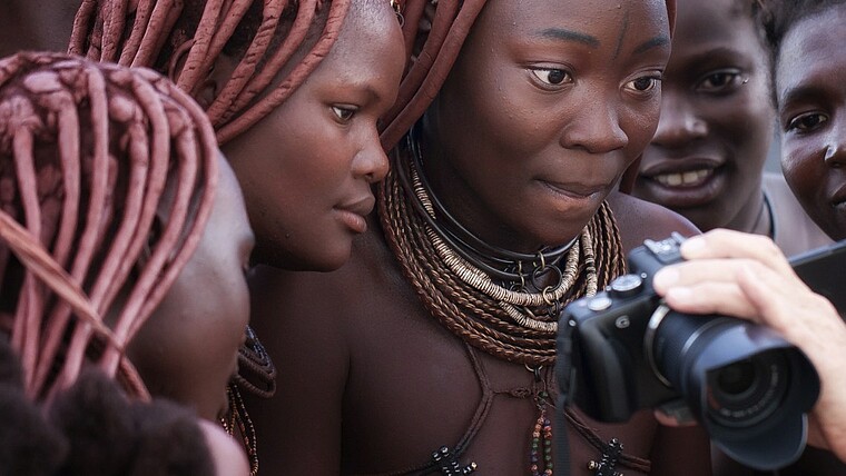 Himba bestaunen Fotos auf einer Kamera in Namibia