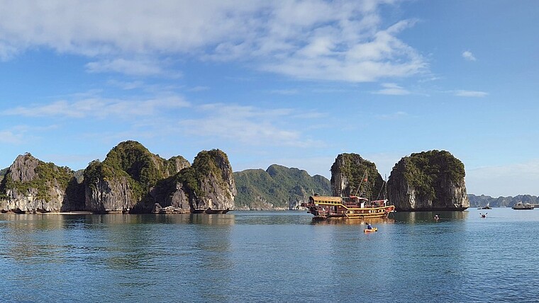 Holzschiff vor den Felsen der Halong Bucht in Vietnam