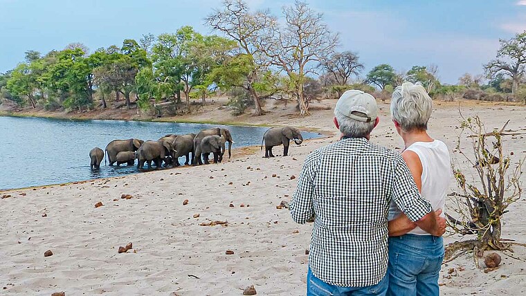 Ehepaar beobachtet Elefanten am Wasserloch in Botswana
