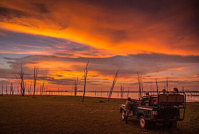 Game Drive Auto mit Touristen beobachtet einen Sonnenuntergang in Matusadona in Zimbabwe