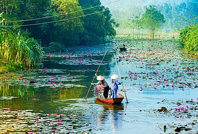 Frauen mit Boot auf dem Yen-Fluss mit Seerosen in Vietnam