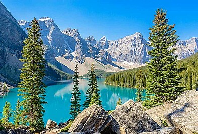 Bergsee mit Fichten vor den Berggipfeln der Rocky Mountains in Alberta, Kanada