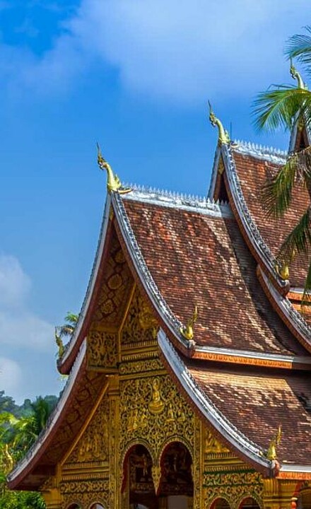Haus mit typisch laotischen Dach vor blauem Himmel in Laos