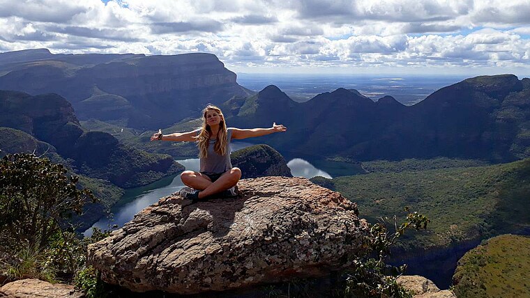Frau sitzt auf einem Stein vor dem Panorama des Blyde River Canyons in Südafrika