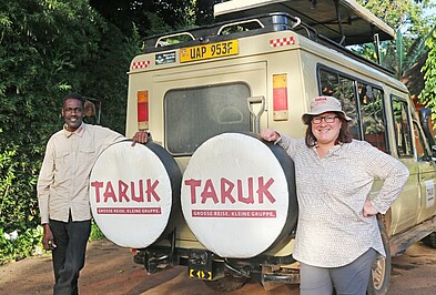 Zwei Personen vor einem Geländewagen in Uganda