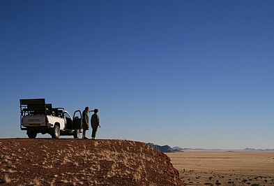 Zwei Menschen mit Geländewagen auf einem Vorsprung mit weiter Assicht in Namibia