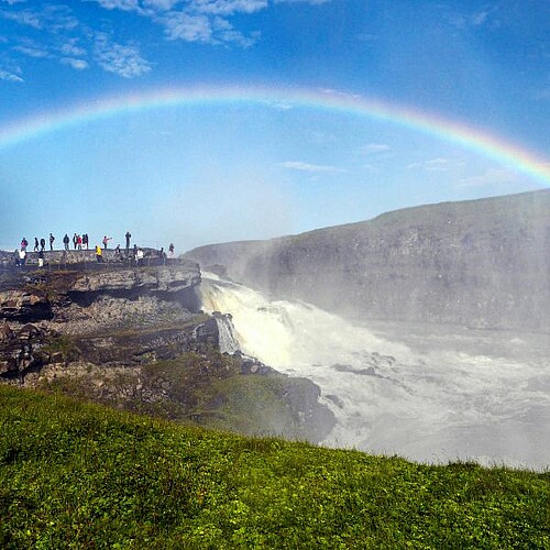 Island Regenbogen rauschender Wasserfall Menschen Gischt