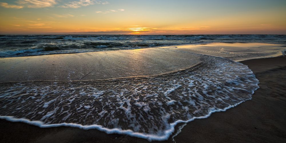 Welle am Strand mit Sonnenuntergang