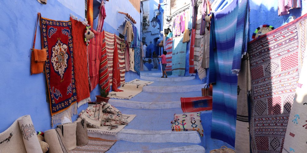 Schmale Gasse mit Teppichen in Chefchaouen in Marokko