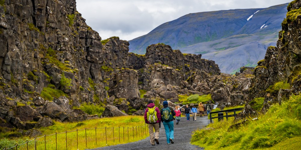 Reisende laufen entlang der Abbruchkante in den Nationalpark Thingvellir