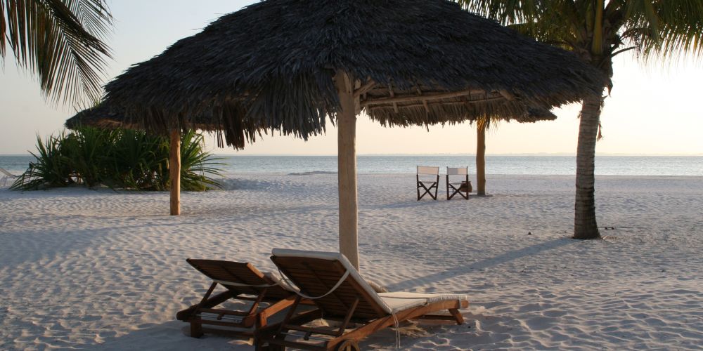 Sonnenliege und Schirm am Strand von Sansibar in Tansania